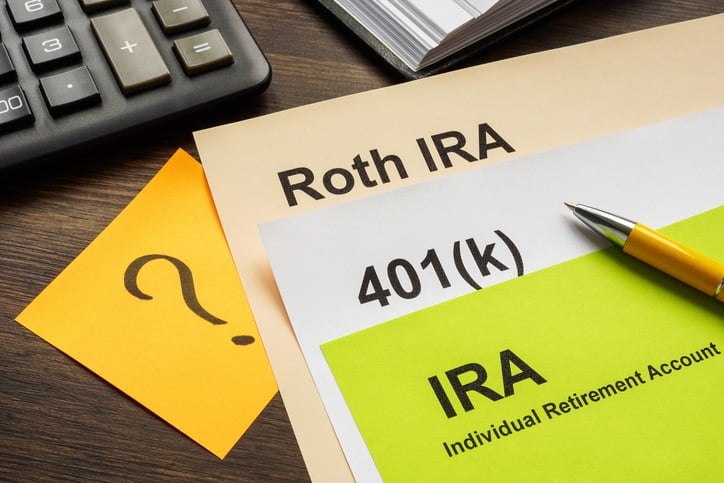 Several pieces of white, yellow, tan, and green paper with “Roth IRA,” “401K,” “?,” and “IRA” written at the top of each.