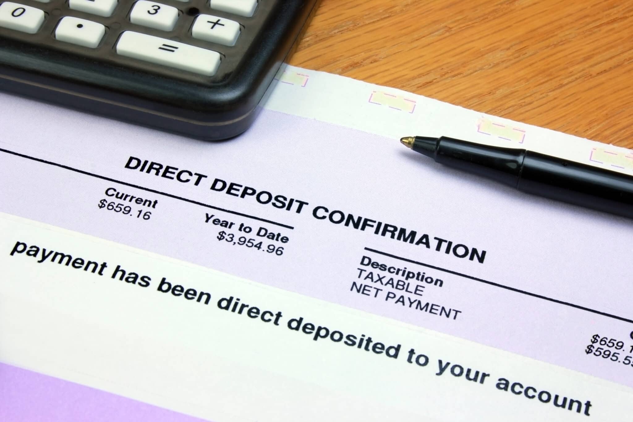 Direct deposit confirmation form beside calculator and pen, showing progress towards auto-savings goals.